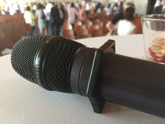 Funkmikrofon mit Rollschutzring microSTOP Star auf dem Tisch in einem vollen Saal